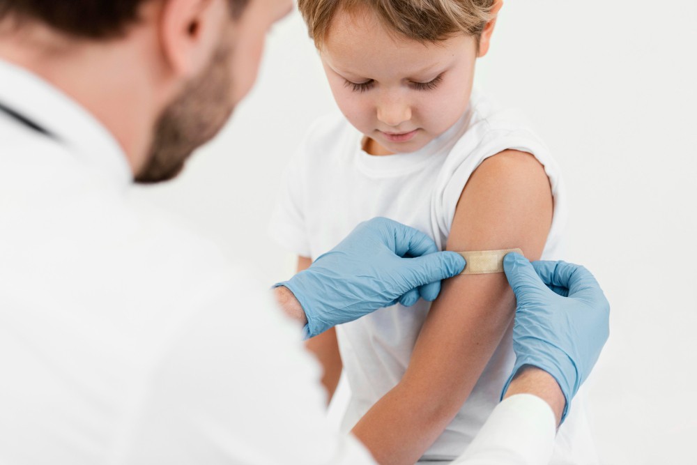 little boy getting a bandage on his arm from his doctor