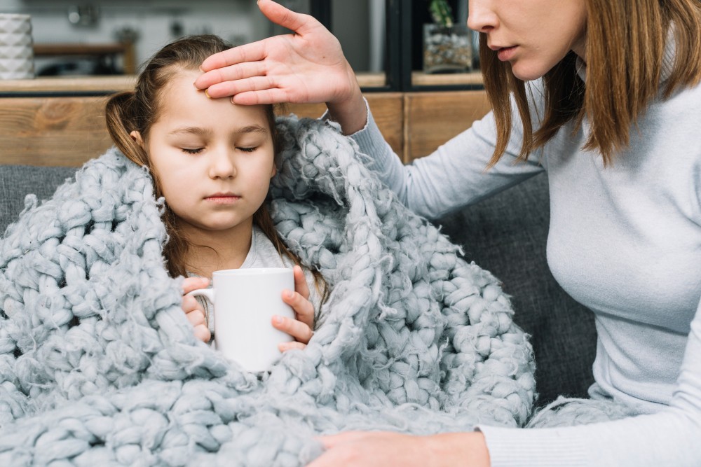 mother checking her daughter's forehead for fever