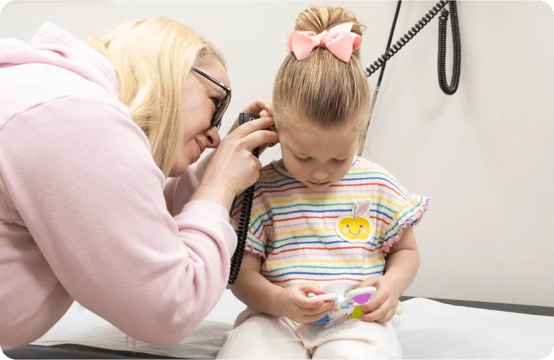 nurse looking into little girls ears at doctor office